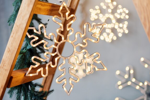 Foto flocos de neve feitos de luzes da guirlanda em cinza rústico com escada de madeira. decoração de natal