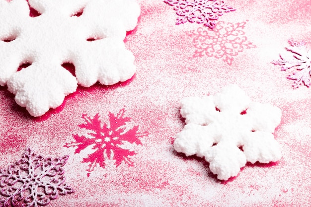 Flocos de neve rosa e brancos em um fundo rosa. fundo de natal. vista do topo. copyspace. neve decorativa.