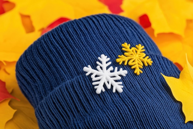 Flocos de nieve en un sombrero de lana con hojas de colores en el fondo