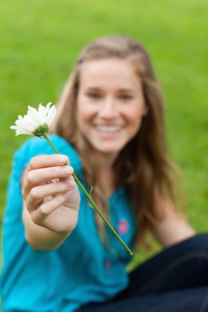 Foto flor blanca en poder de una joven mujer sonriente
