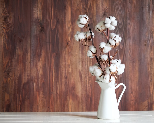 Flor de algodão em um frasco branco sobre uma mesa branca