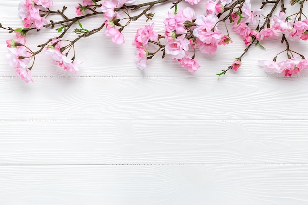 Flor de cerejeira em um fundo branco de madeira. borda de quadro floral. modelo com espaço de cópia. padrão romântico com lugar para texto. brincar. disposição da mola. cartão de dia das mães. ramos de sakura.