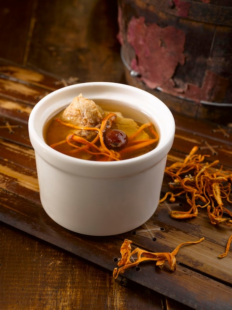 Foto flor de cordyceps doubleboiled com sopa de galinha servida em uma tigela isolada na vista lateral da mesa