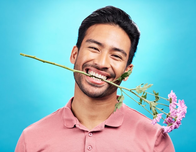 Flor de dentes e feliz com retrato de homem em estúdio para presente de celebração e romance Engraçado pateta e presente com macho isolado em fundo azul para sorriso de felicidade e maquete de dia dos namorados