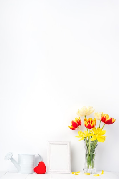 Flor de tulipa em vaso de vidro com moldura na parede branca, conceito de decoração do dia das mães.