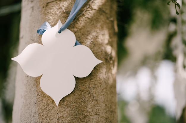 Flor decorativa de papel branco pendurada em uma fita em um pilar decorações de casamento
