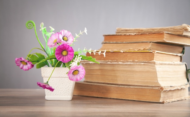 Flor e livro na mesa de madeira.