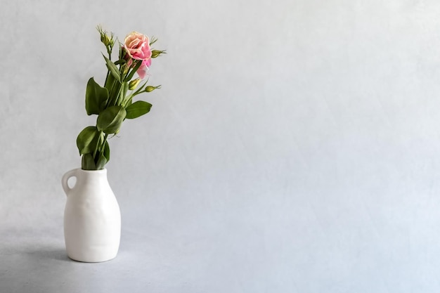 Flor em um vaso de cerâmica branco em um fundo cinza cravo rosa em um vaso photo