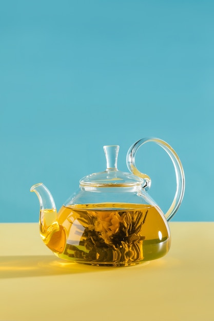 Flor floreciente del té verde en la foto de alta calidad de la tetera de cristal