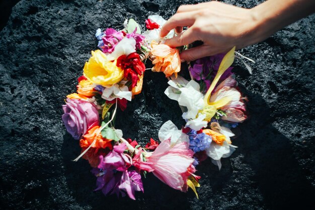 La flor hawaiana lei en las rocas de lava con una mano en Kauai, Hawai