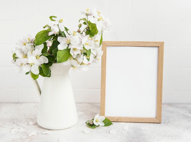 Flor de manzana de primavera en un jarrón con un marco de fotos vacío sobre la mesa