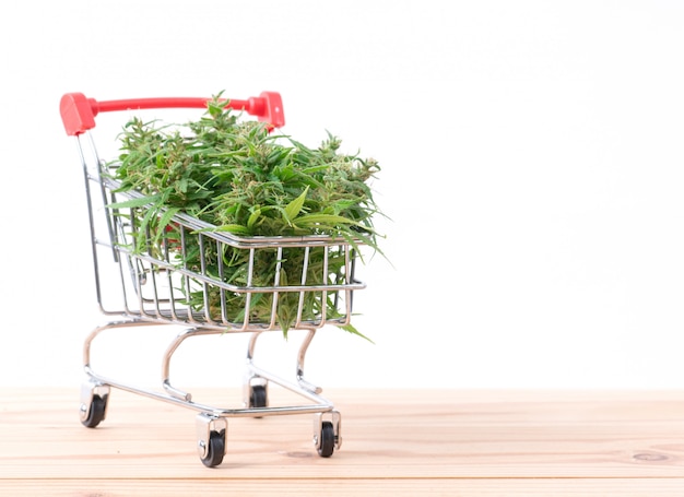 Foto flor de marihuana en carrito de compras en mesa