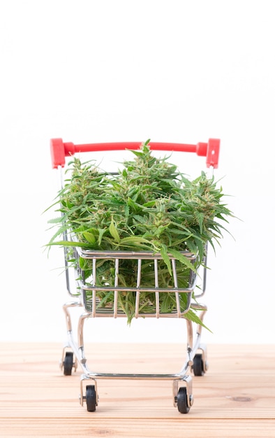 Flor de marihuana en carrito de compras en mesa