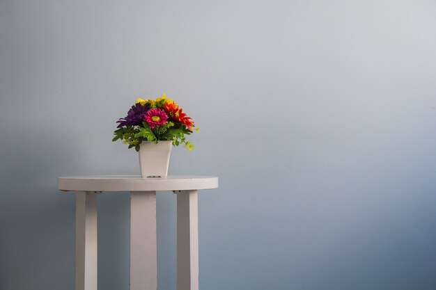 Flor en la mesa pared blanca fondo azul