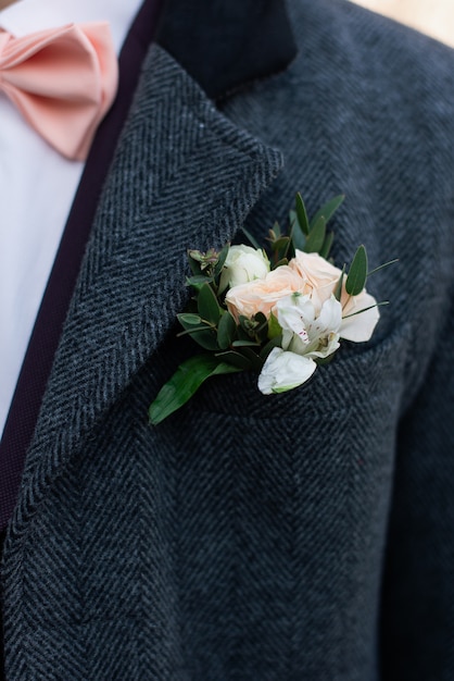 Foto flor en el ojal de rosa rosa en el abrigo de la boda del novio