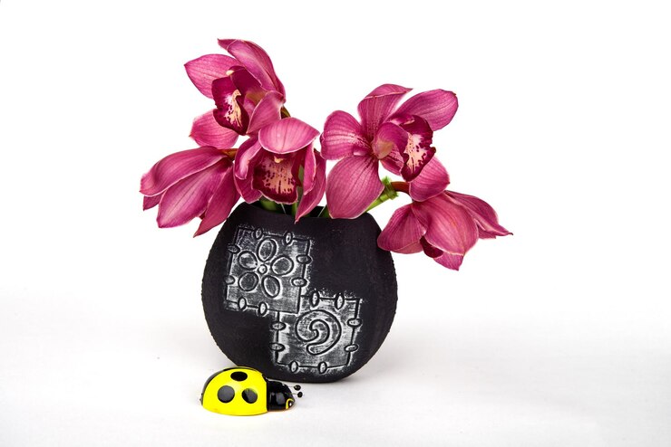 Foto una flor de orquídea en un jarrón negro juguetes de recuerdo para decorar mesas vacaciones valen artificial