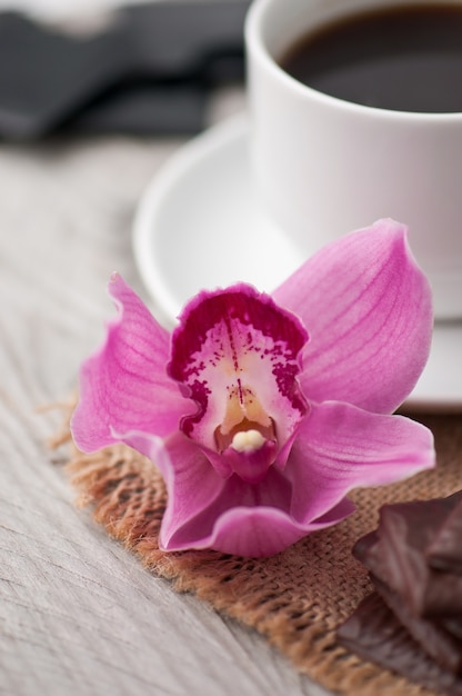 Flor de orquídea rosa y taza de café