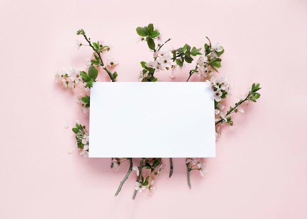 Flor de primavera y tarjeta blanca en blanco sobre fondo de melocotón Imagen de maqueta