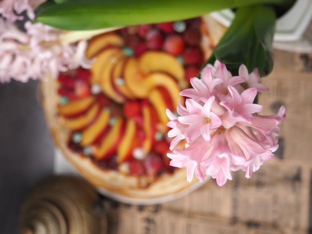 Una flor rosa está frente a un pastel con fresas.