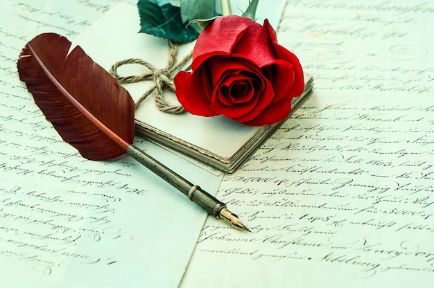 Flor rosa roja, letras antiguas y bolígrafo antiguo. fondo romántico de la vendimia. enfoque selectivo