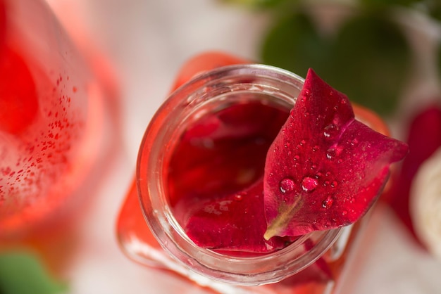 Flor de rosa rosa y vaso de agua de rosas Agua de rosas orgánica fresca Agua de rosas en botella de vidrio