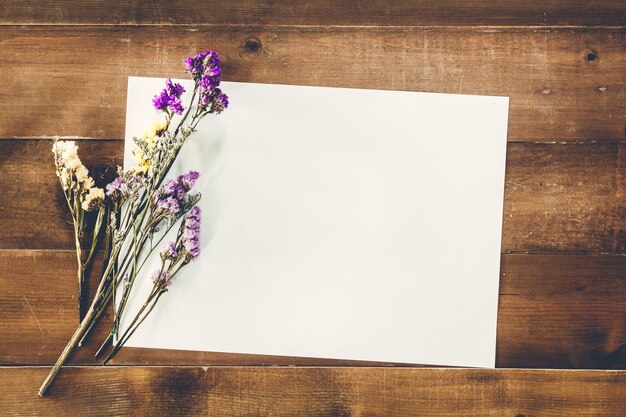 Flor seca con papel en la mesa de madera