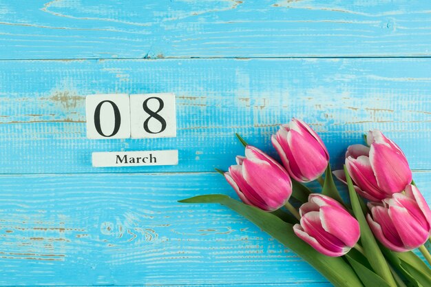 Flor tulipa rosa e 8 de março calendário sobre fundo azul mesa de madeira com espaço de cópia de texto. Conceito de dia internacional do amor, igualdade e mulheres