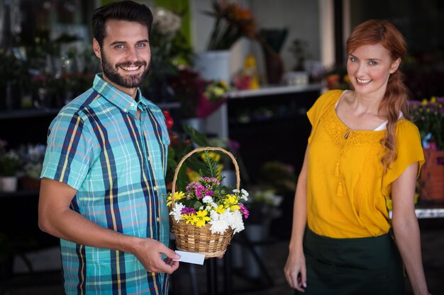 Floreria y cliente con canasta de flores y tarjeta de visita