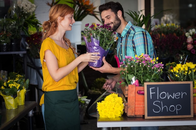 Floreria femenina dando ramo de flores al hombre