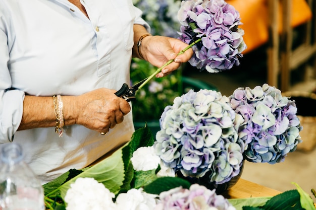 Floreria femenina haciendo hermosos bouquetes mientras está de pie en la tienda de flores