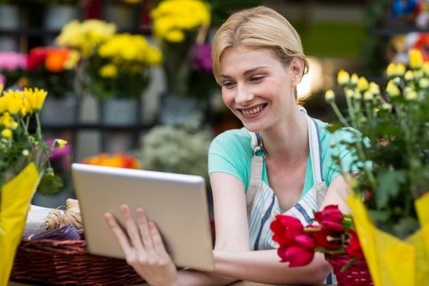 Floreria femenina con tableta digital en floristería