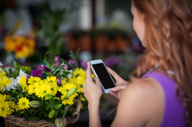 Floreria femenina tomando photogrpah de canasta de flores