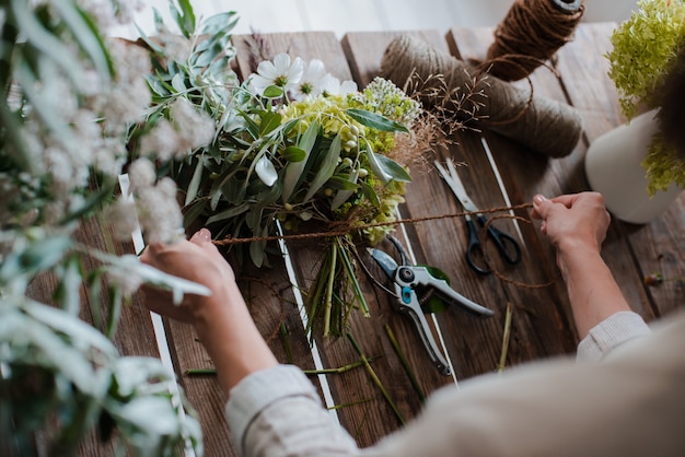 Floreria profesional femenina prepara el arreglo de flores silvestres.