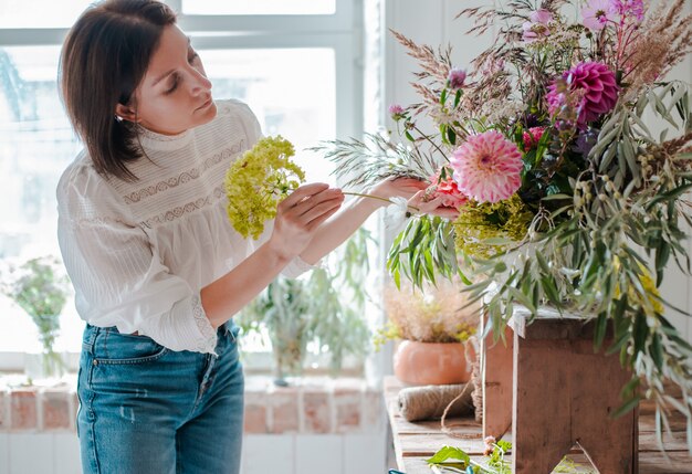 Floreria profesional femenina prepara el arreglo de flores silvestres.