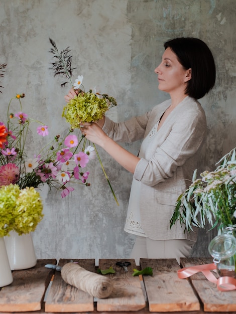 Floreria profesional femenina prepara el arreglo de flores silvestres.