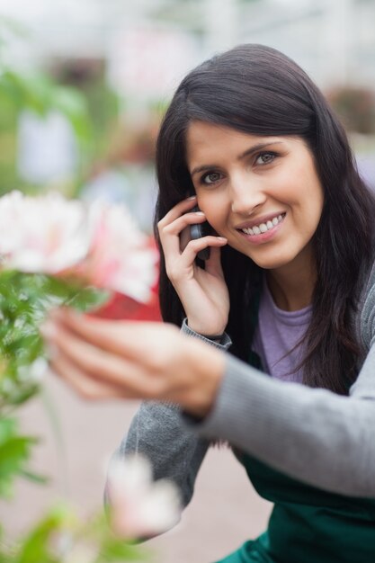 Floreria sonriente tocando una flor y haciendo una llamada