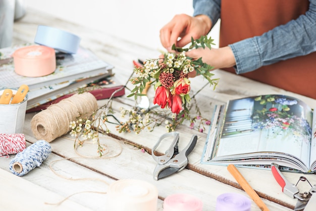 Floreria en el trabajo: las manos femeninas de mujer haciendo moda moderno ramo de flores diferentes