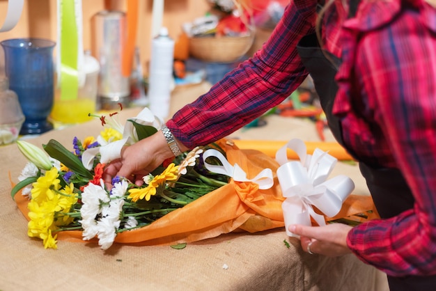 Floreria en el trabajo. Manos de mujer haciendo hermoso ramo de flores.