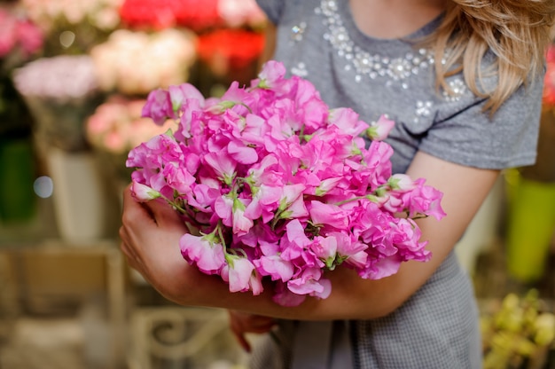 Floreria en un vestido gris con un hermoso y tierno ramo de flores de color rosa