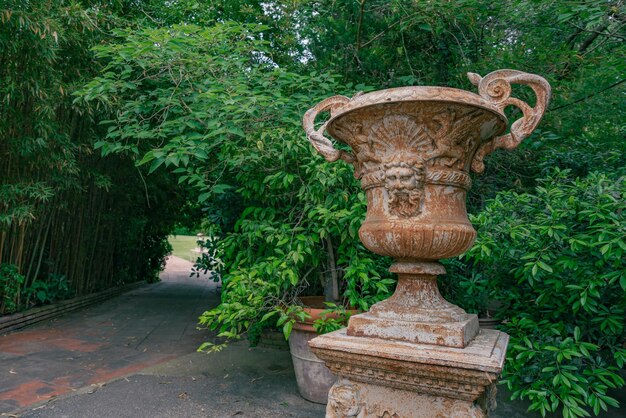 Foto florero decorativo viejo en el jardín al lado del bambú