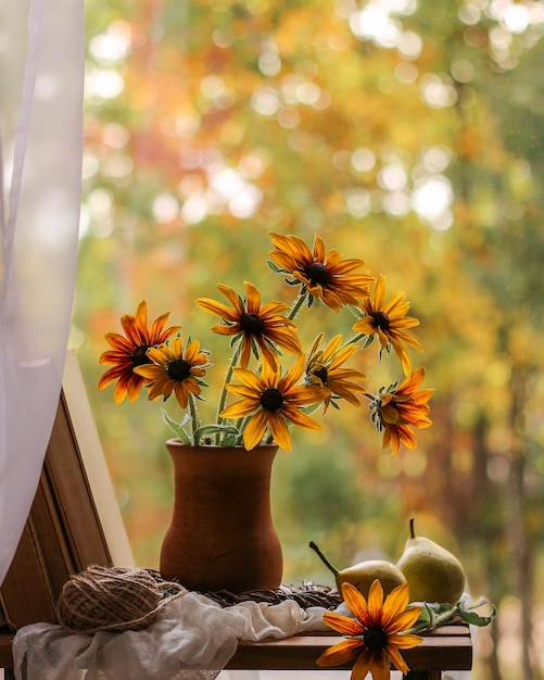 Florero con flores amarillas y libros sobre el fondo de la naturaleza otoñal Bodegón otoñal