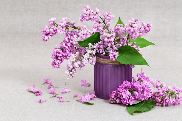 Florero con flores lilas sobre fondo de tela con espacio de copia. Flores de color rosa lilas.