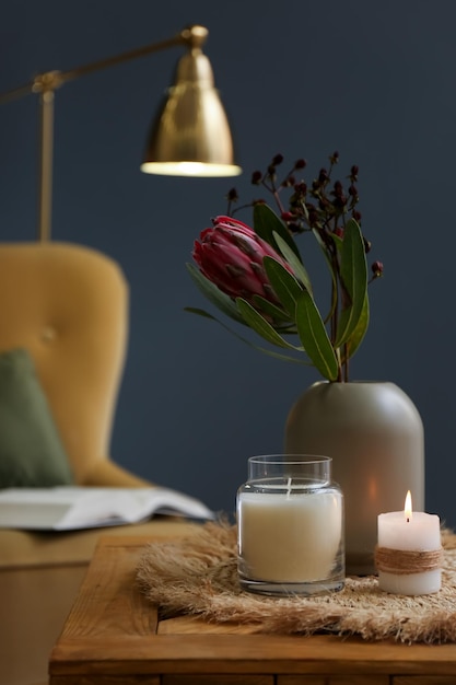 Florero con hermosas flores de protea y velas sobre una mesa de madera en el interior Elementos interiores