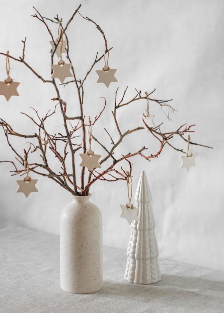 Florero interior navideño con ramas y adornos navideños de estrellas caseras en la mesa de la sala de estar