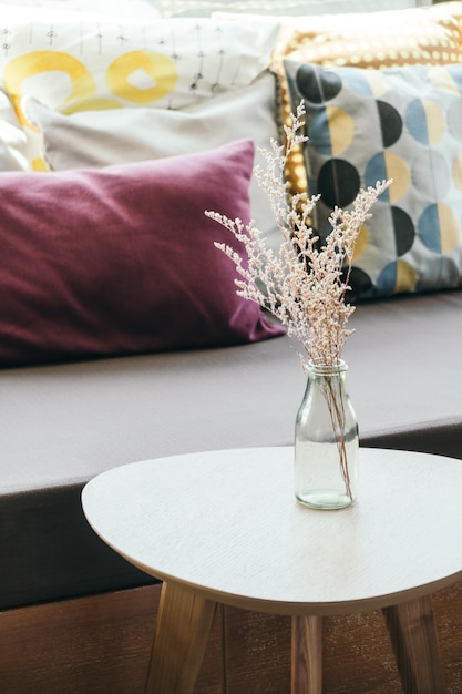 Foto florero en la mesa de decoración con almohada y sofá