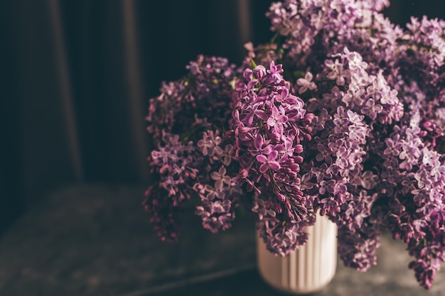 Florero con un ramo de flores lilas de primavera de cerca