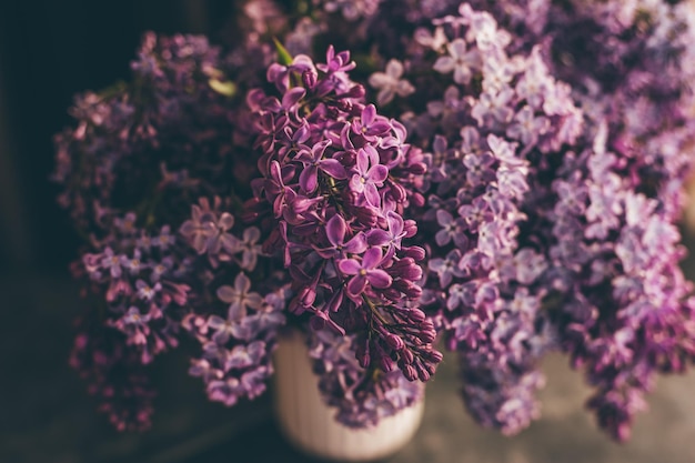 Florero con un ramo de flores lilas de primavera de cerca