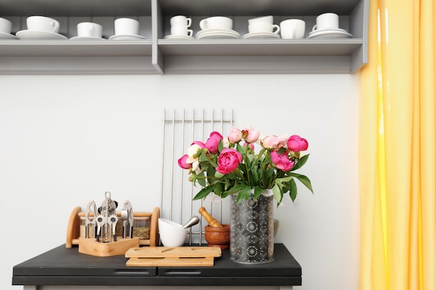 Florero con ramo de hermosas peonías en el mostrador de la cocina