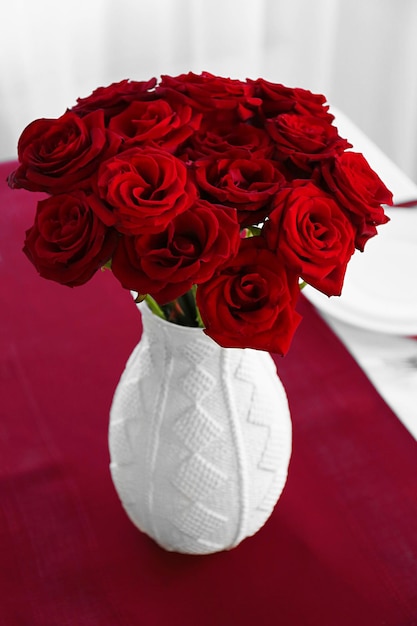 Florero con rosas rojas en una mesa servida de vacaciones