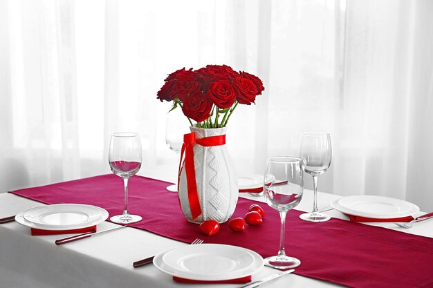 Florero con rosas rojas en una mesa servida de vacaciones